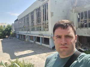 Kevin in a selfie in front of a sport complex in Kharkiv he says was destroyed by Russians early in the war.